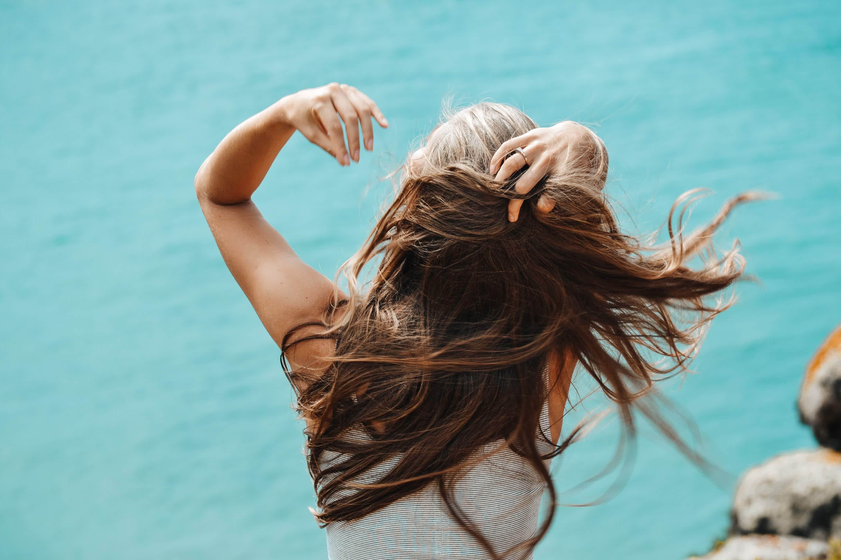 Back View Photo of Woman in White Sleeveless Shirt Running Her Fingers Through Her Hair