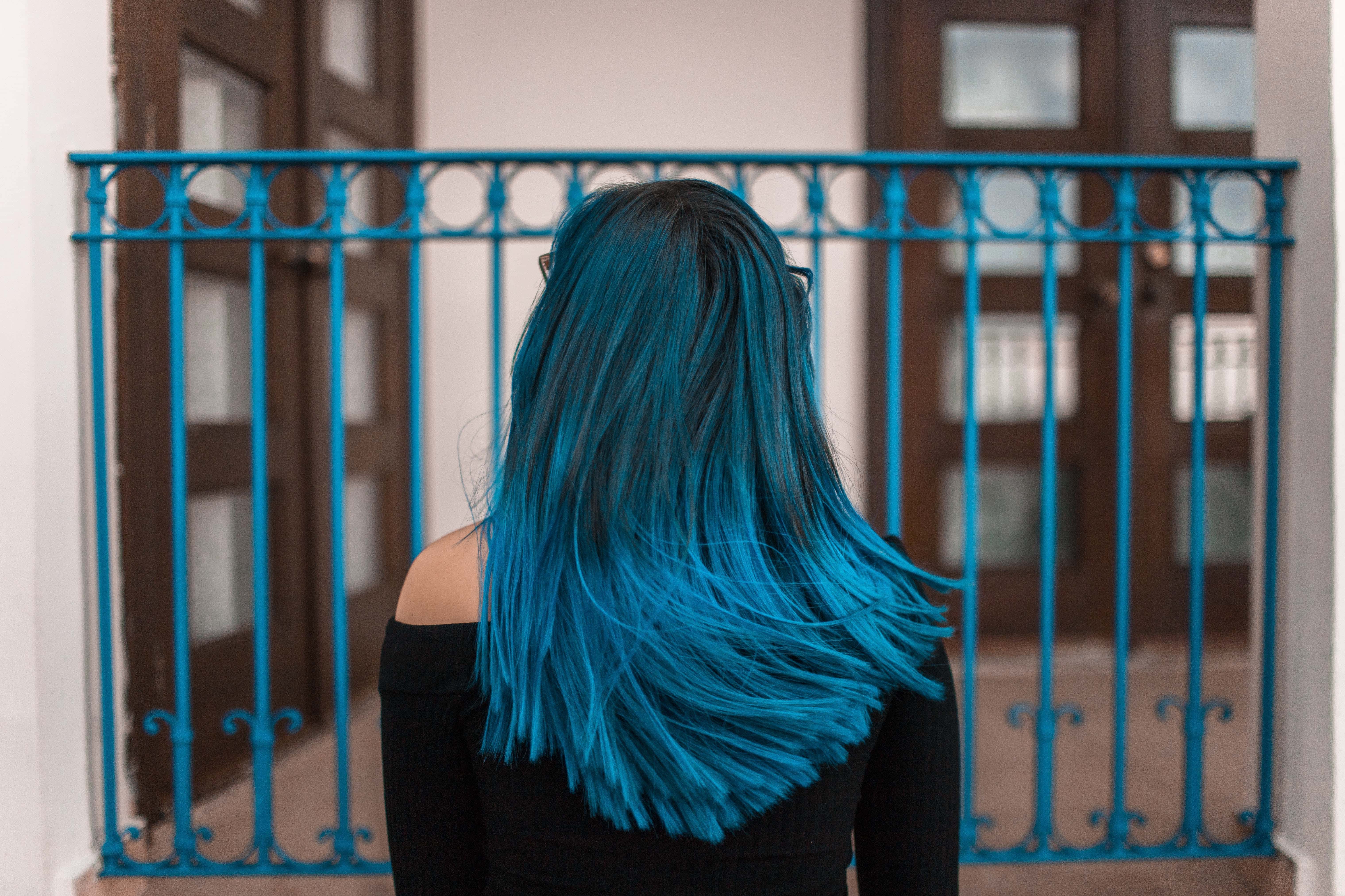 Blue Haired Woman Facing Metal Fence